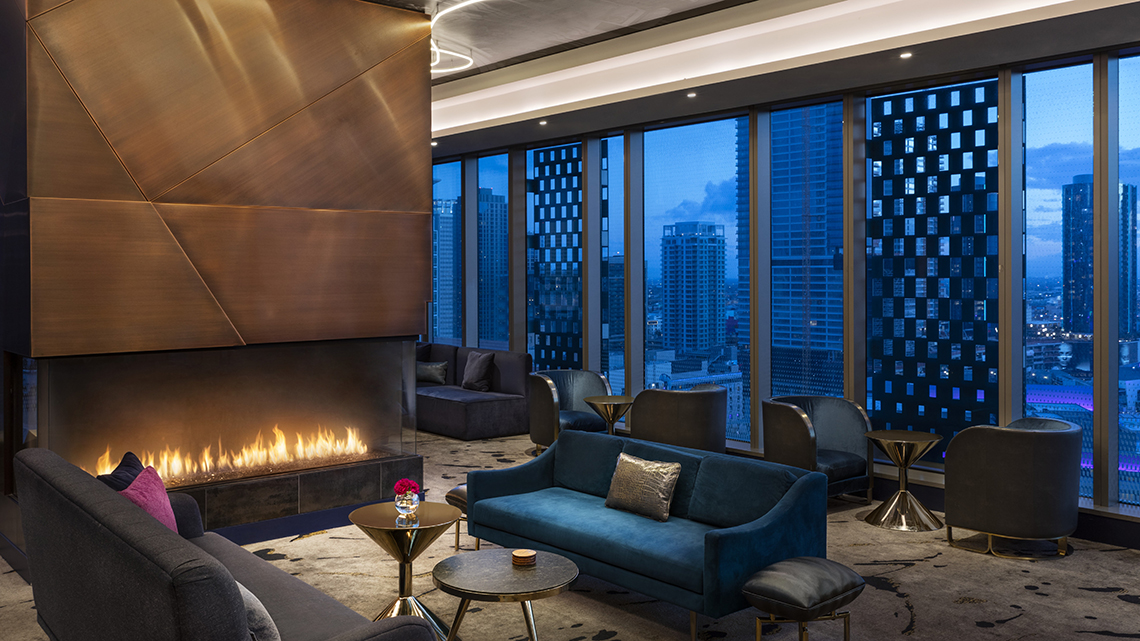 luxurious hotel suite with a roaring fireplace and a high cityscape view