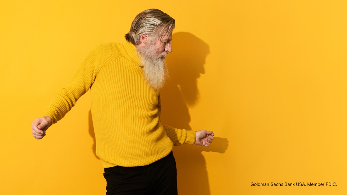 Un hombre mayor baila sobre un fondo amarillo.