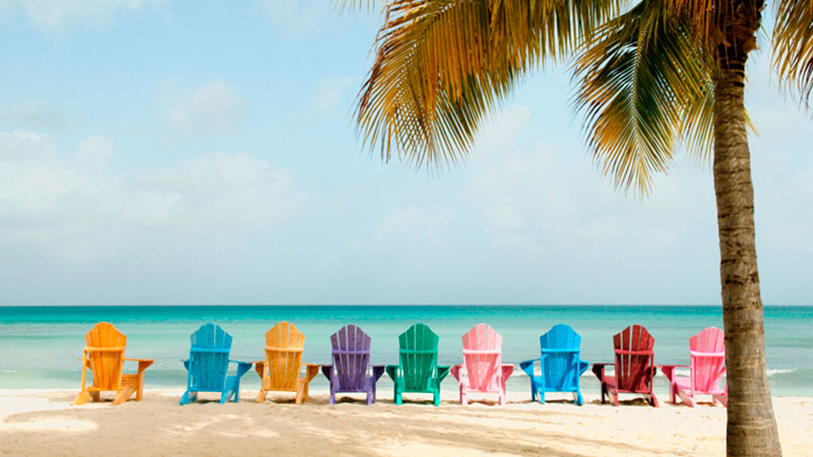 Nine colorful beach chairs sitting on the beach facing the water