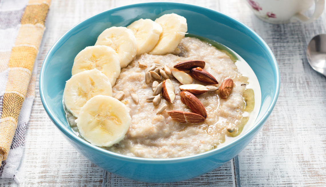 A bowl of oatmeal with bananas and almonds.