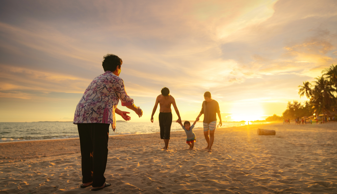 Couple with small child and grandmother on the beach at sunset