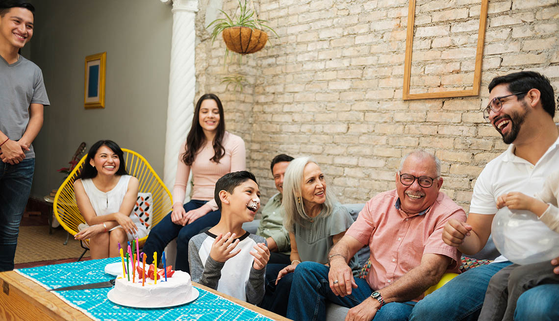 a family sitting around a birthday cake laughin