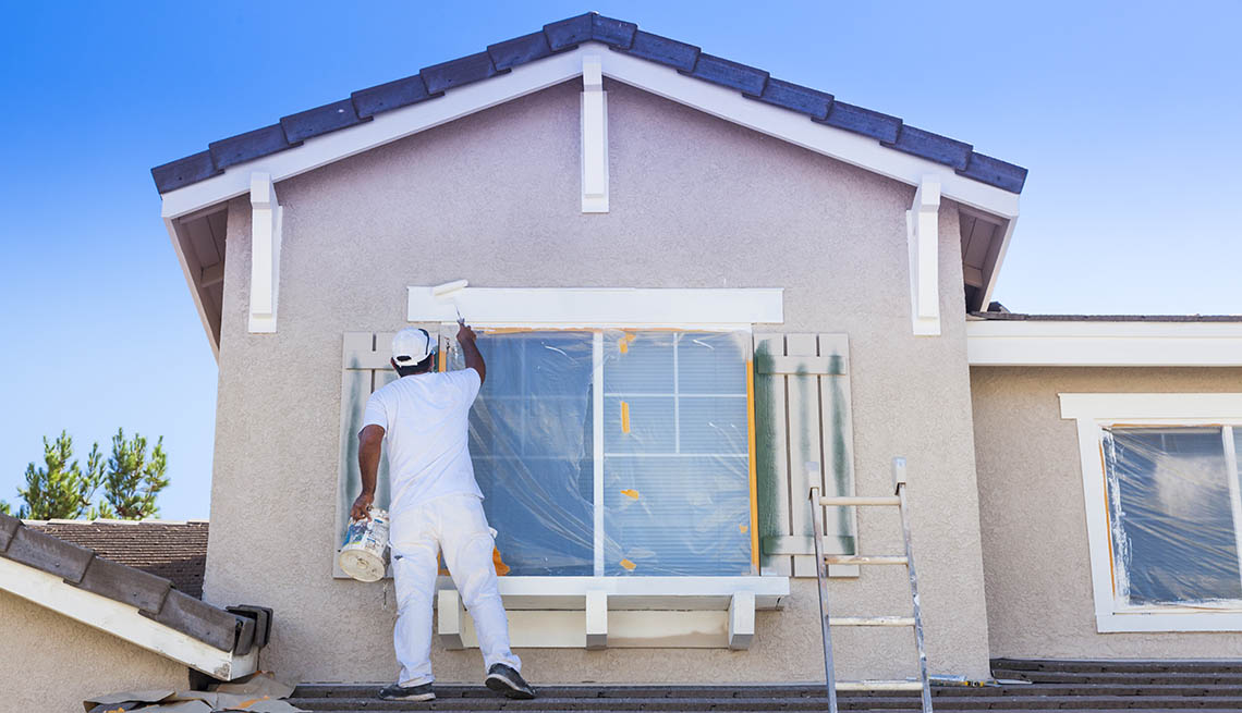 House painter painting the trim and shutters of a home.