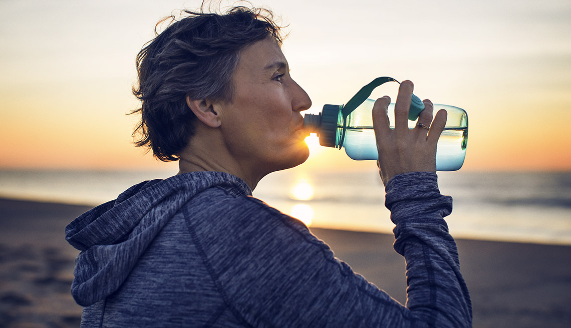 A woman drinking water on the beach