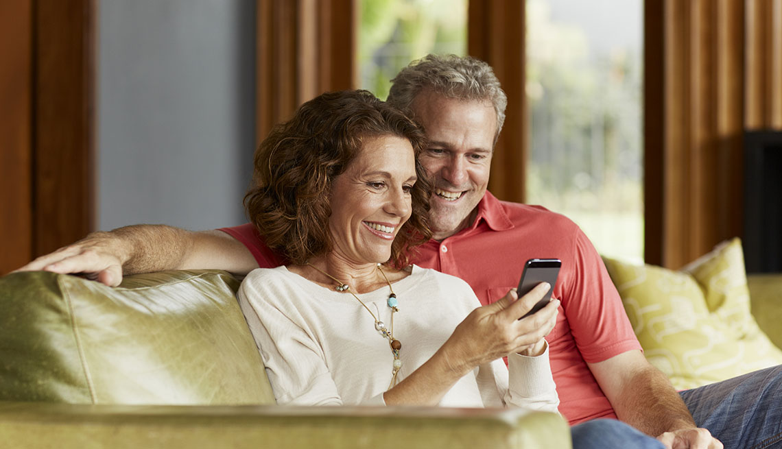 Couple using mobile phone while relaxing on sofa at home