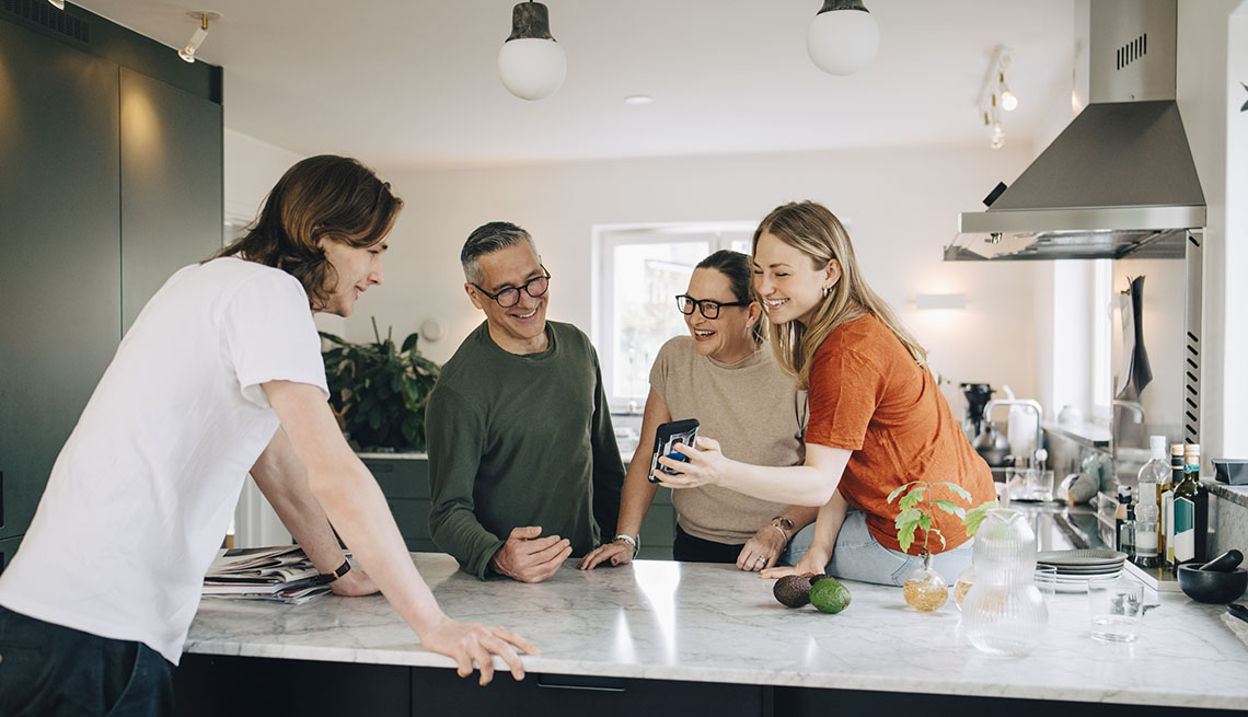 Family in kitchen looking at a phone