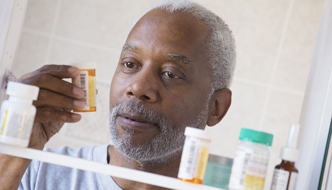 A man examining prescription bottle in medicine cabinet