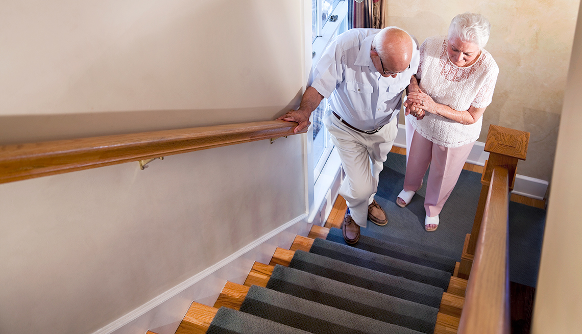 Mujer ayuda a un hombre mayor a subir las escaleras