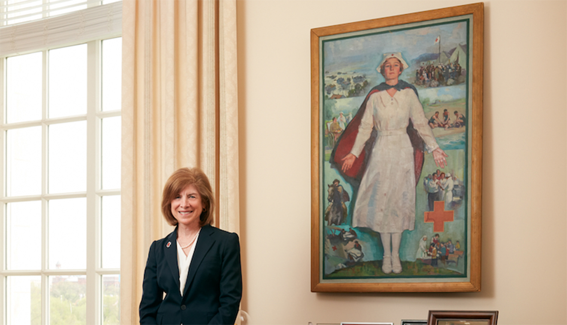 American Red Cross CEO Gail McGovern standing by a painting of a Red Cross nurse.