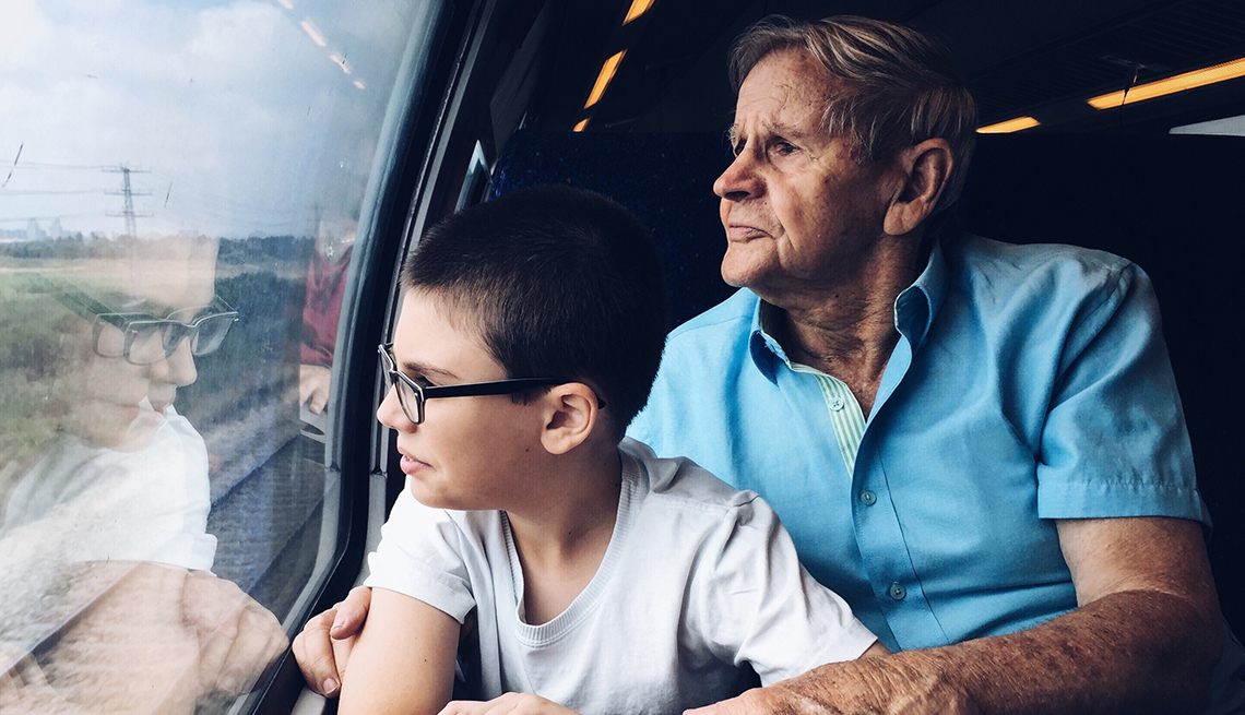 Un abuelo viajando en tren con su nieto.