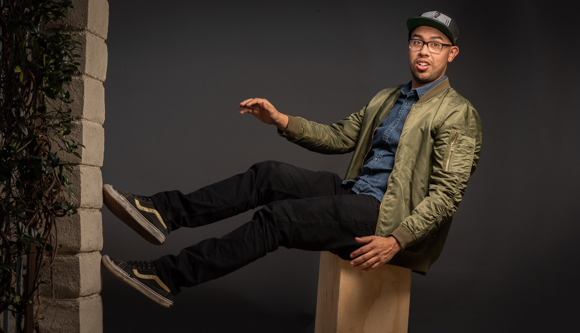 item 9 of Gallery image - Comedian Jesus Trejo sitting on a box, tipping backwards.
