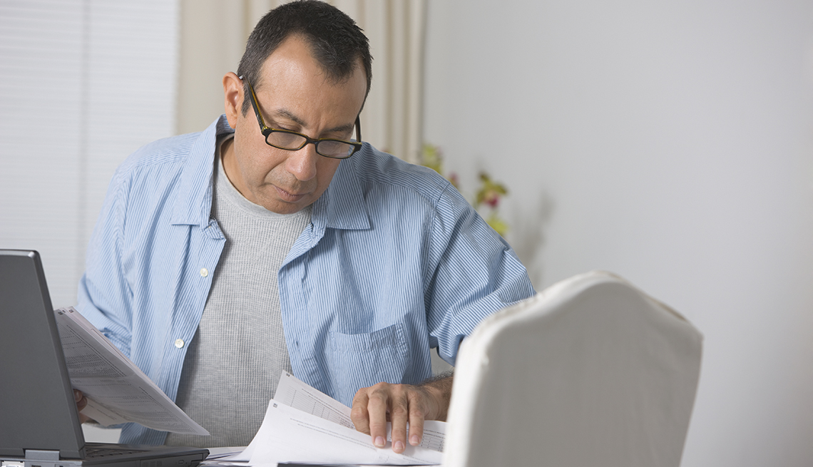 Hombre mirando unos documentos frente a su computadora
