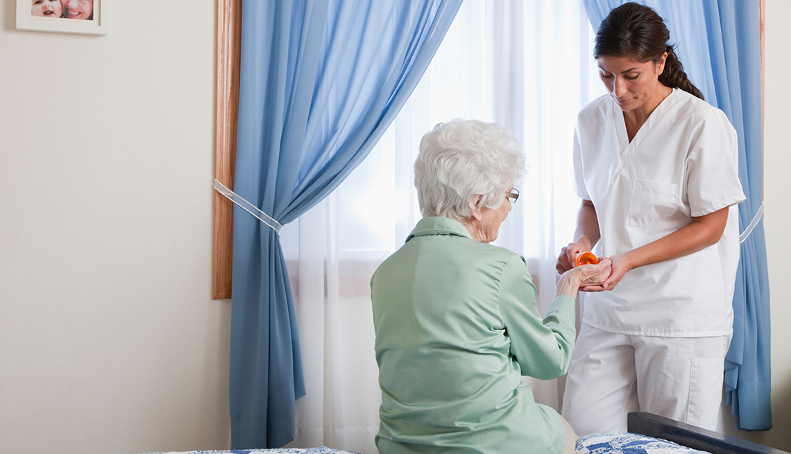 Enfermera dándole un medicamento a una mujer mayor