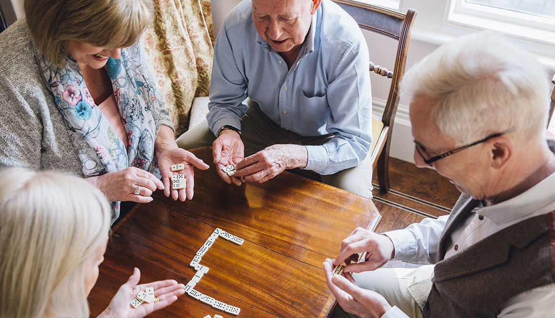 Dos hombres y dos mujeres mayores juegan dominó