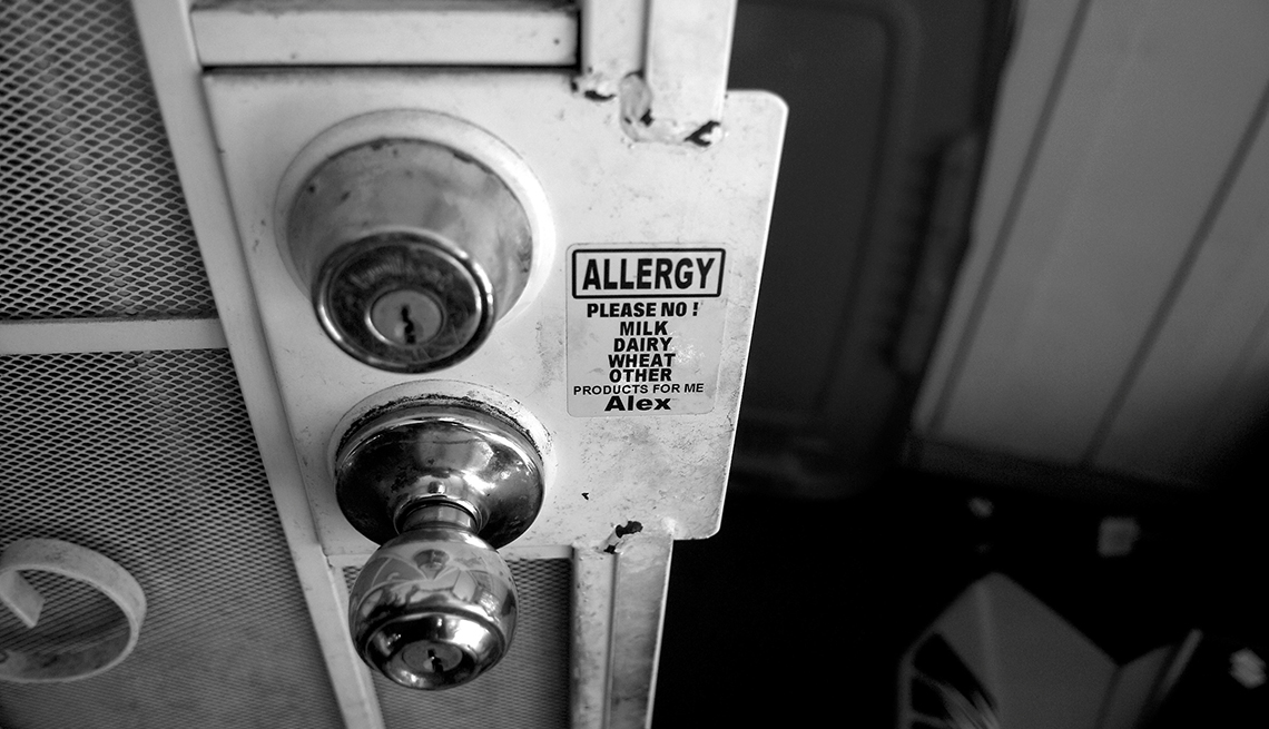 A sticker on a front door gate reading allergy - please no milk, dairy, wheat products for Alex