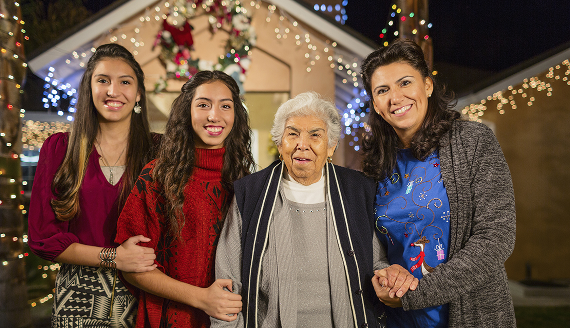 Tres generaciones de mujeres paradas frente a su casa decorada de Navidad