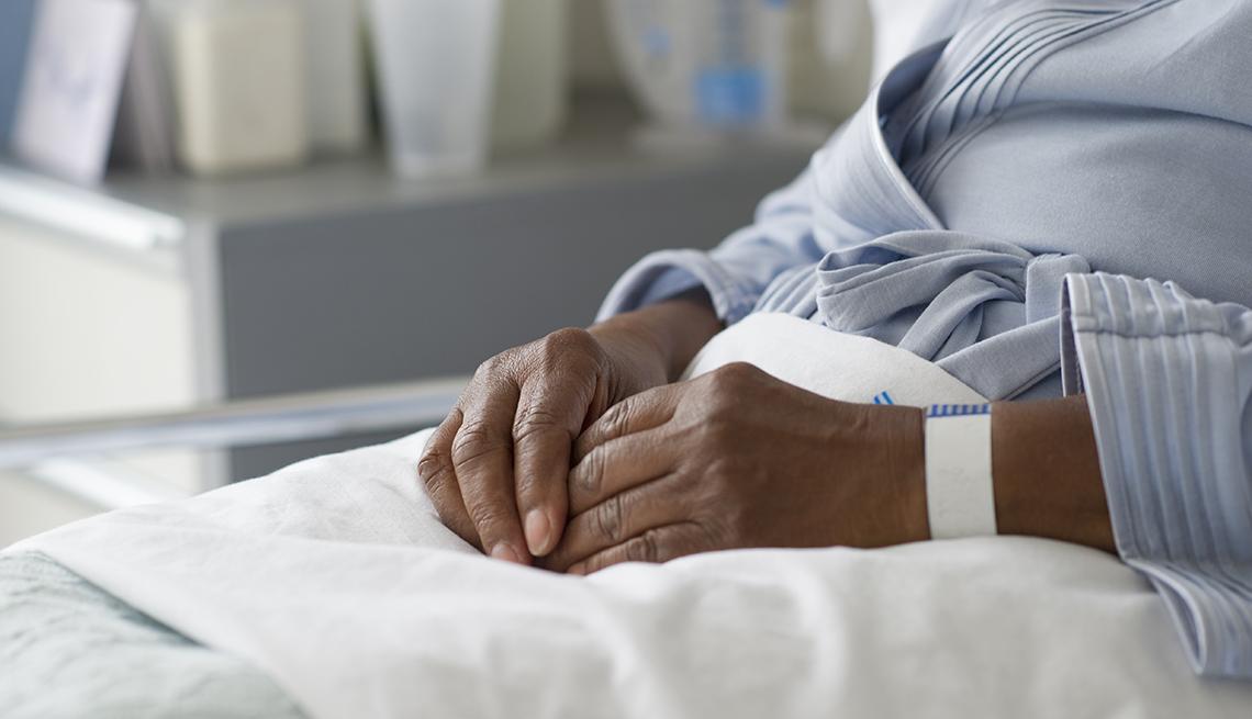 Close up of the hands of a woman laying in a nursing home hospital bed