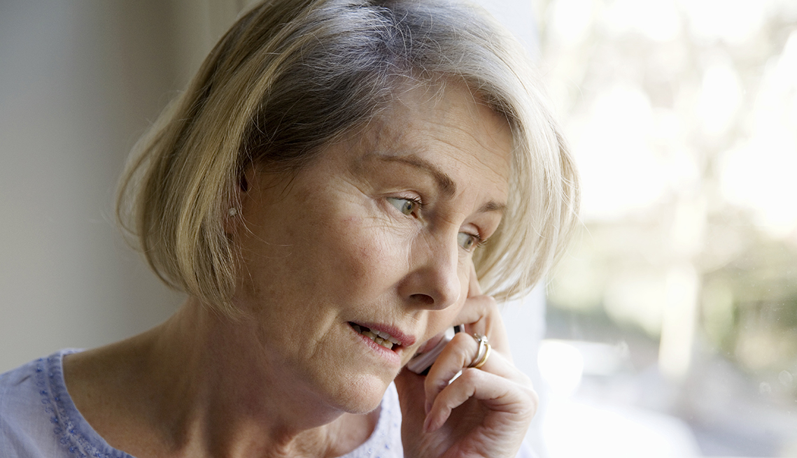 A worried looking woman on the telephone with an assisted living facility
