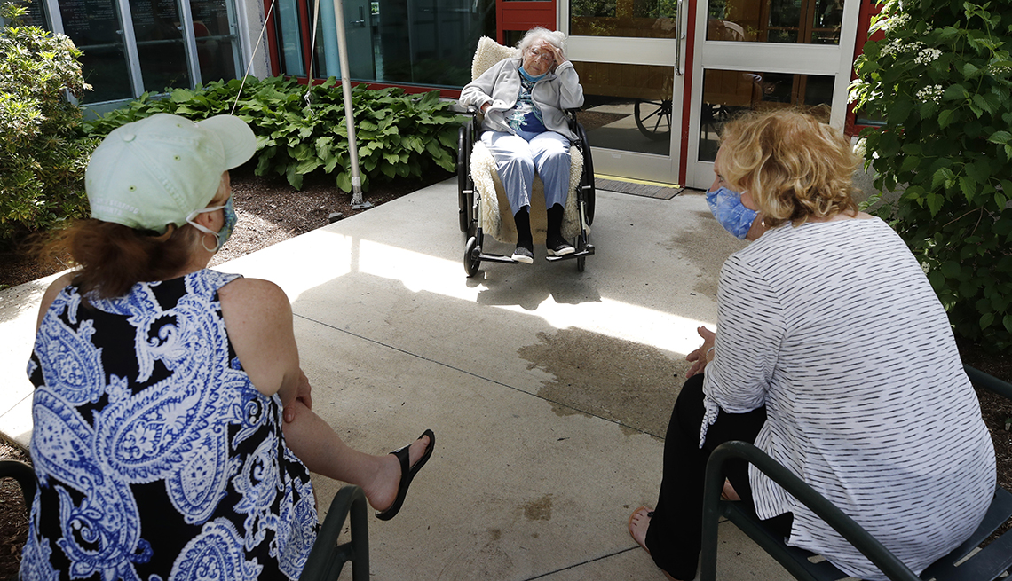 Dos mujeres con mascarillas visitan a su madre fuera de un hogar de ancianos