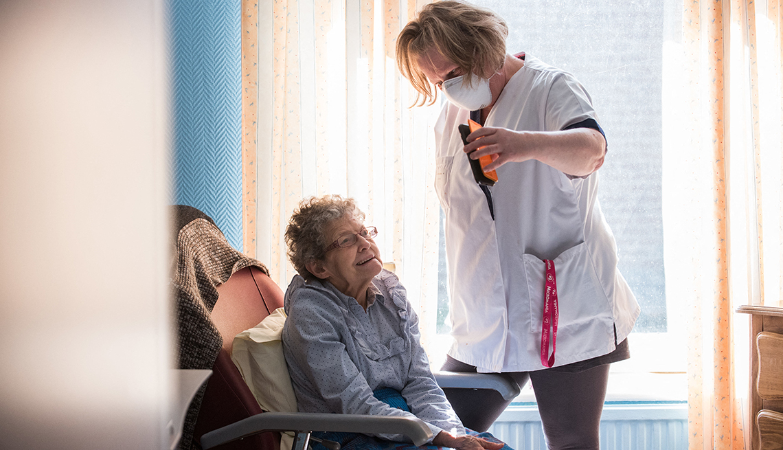 A nursing home aide holds a phone to assist a nursing home resident with a virtual visit