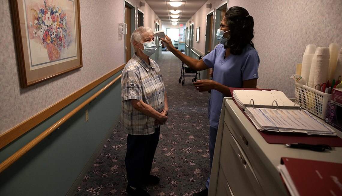 Una enfermera le toma la temperatura a una residente de un hogar de ancianos