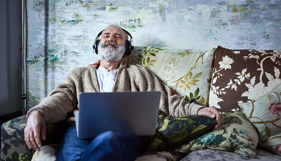 Cuidador de familia se relaja en su sofá escuchando música a través de auriculares.