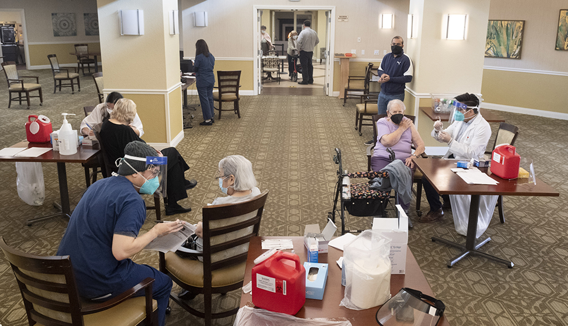 three nursing home residents at different tables getting covid vaccine shots