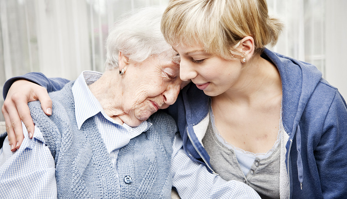 caring photo of older woman with head on shoulder of younger woman