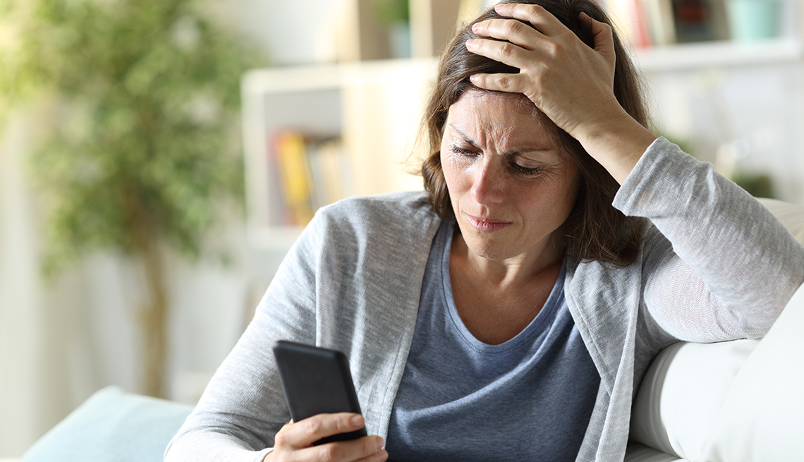Una mujer mirando su teléfono un mensaje de texto con frustración.