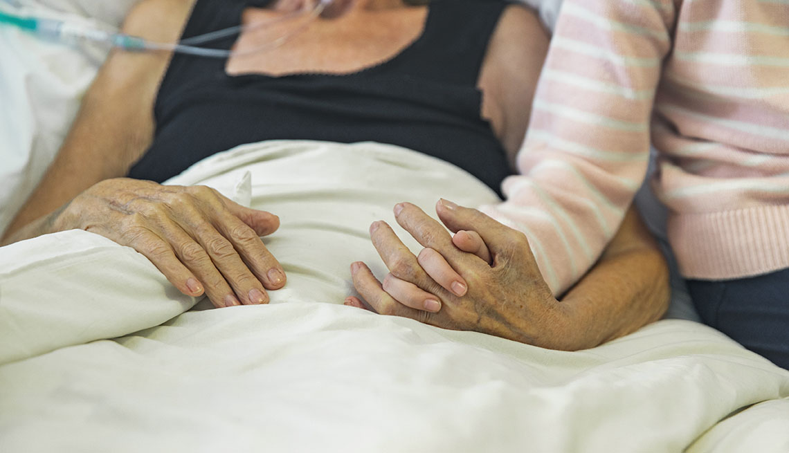 woman holding hospice patient's hand