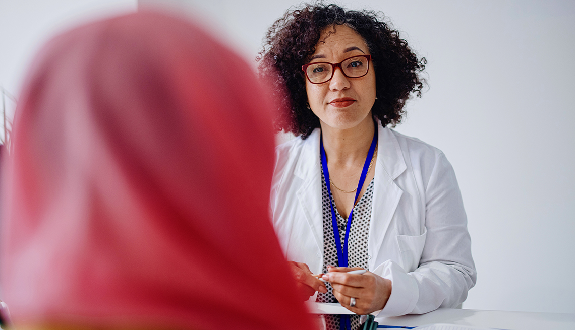 Una mujer musulmana se sienta frente a su médico mientras habla con ella.