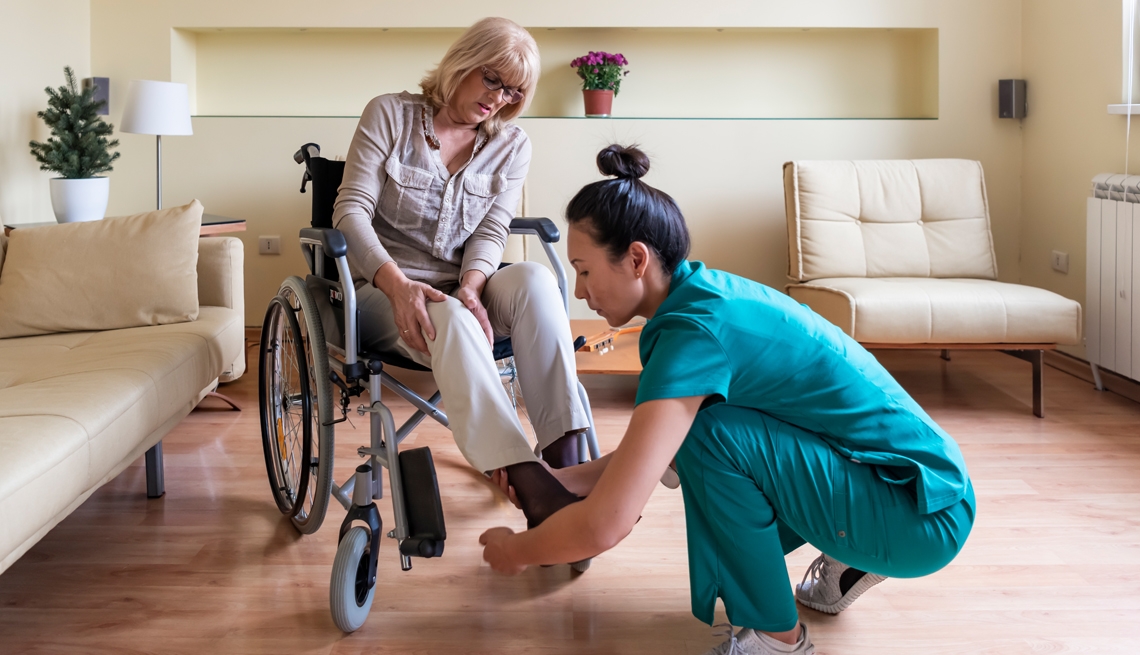 Una trabajadora de asistencia domiciliaria que ayuda a una persona en silla de ruedas en su hogar.