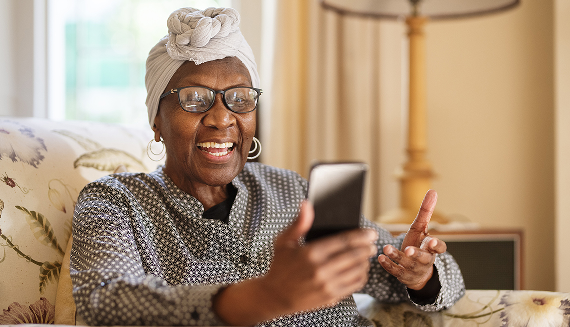 Una mujer mayor hace una video llamada desde su teléfono celular.