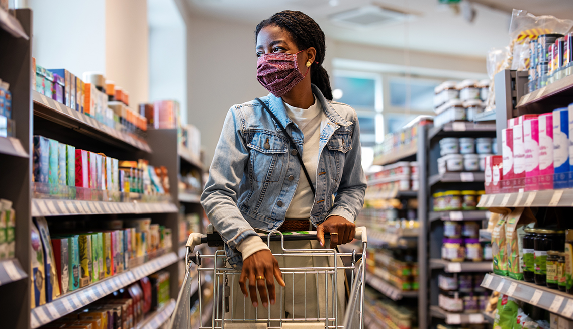 a woman wearing a face mask goes grocery shopping