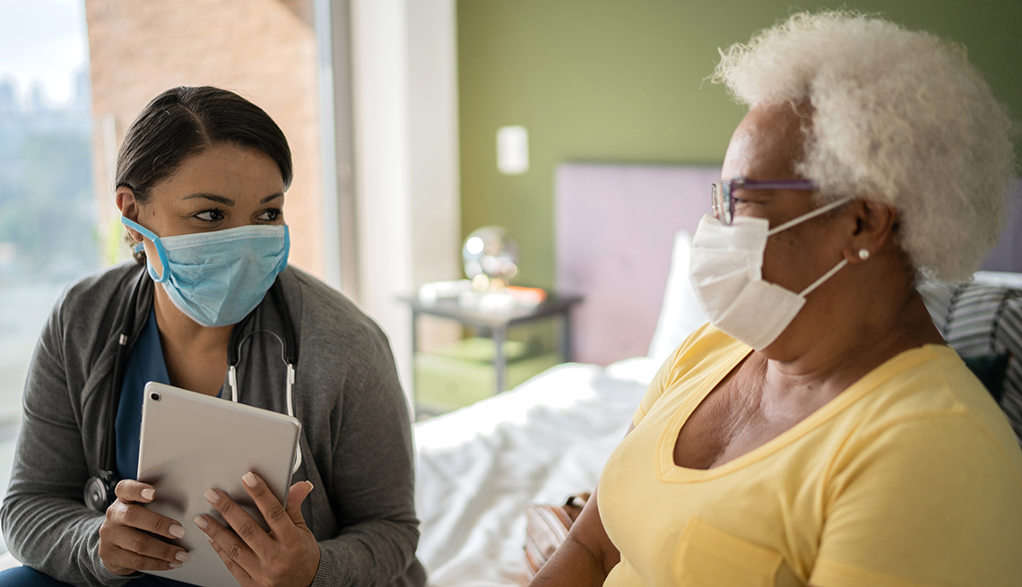 doctor talking to patient in nursing home both are wearing surgical face masks