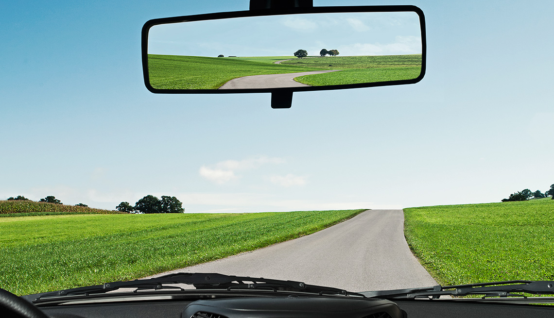 rear view mirror and open road as seen from front seat of car