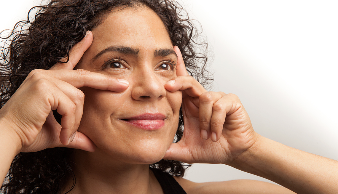 Woman with hands on her cheeks doing face aerobics