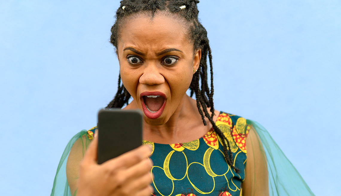Horrified looking young woman gawping wide eyed at her mobile phone