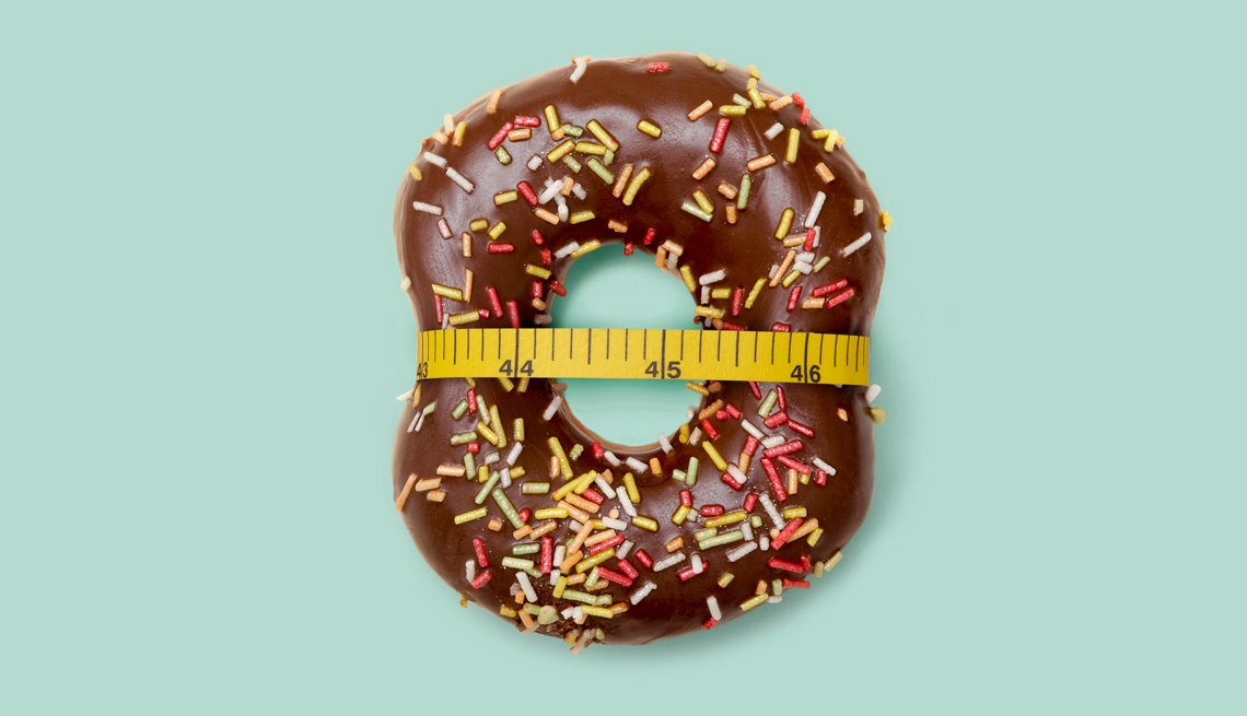 A chocolate donut with sprinkles with a tape measure ...