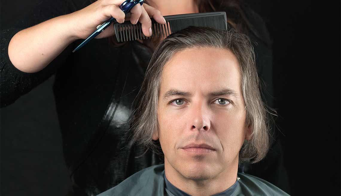Estilista haciendo un corte a un hombre de cabello largo - Cuidado del cabello para hombres de 50 años o más