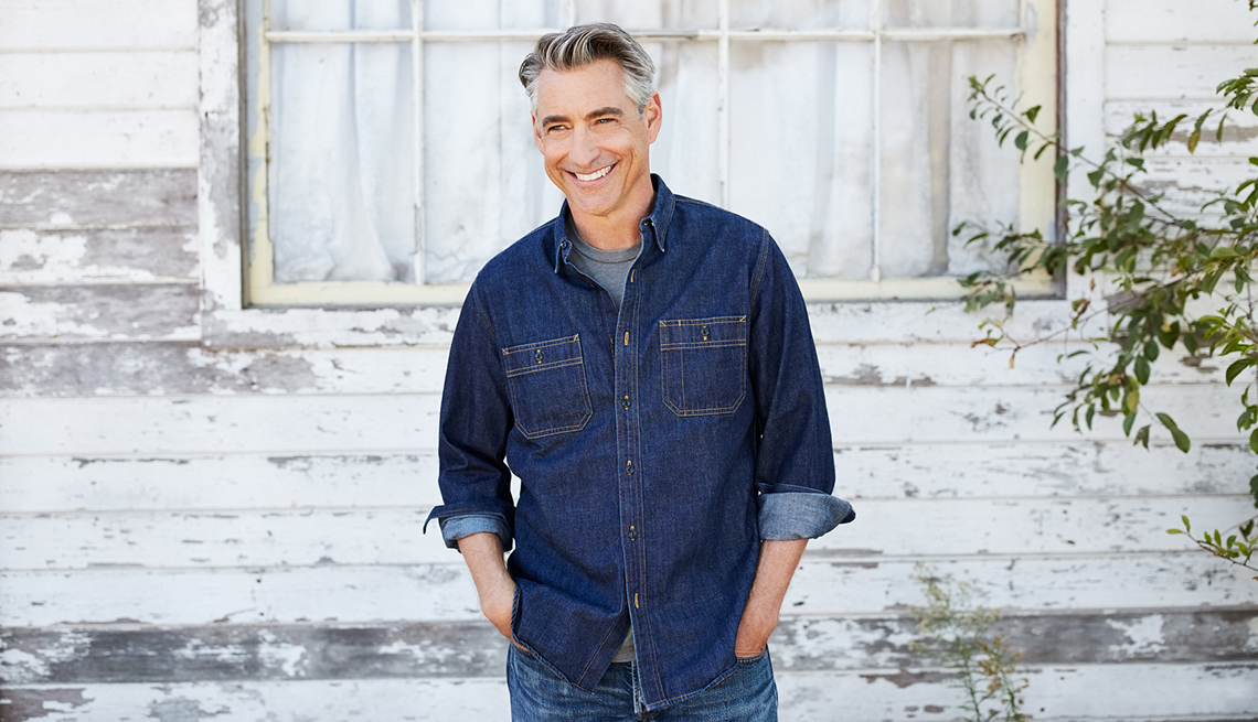 Hombre sonriendo y usando una camisa de jean.