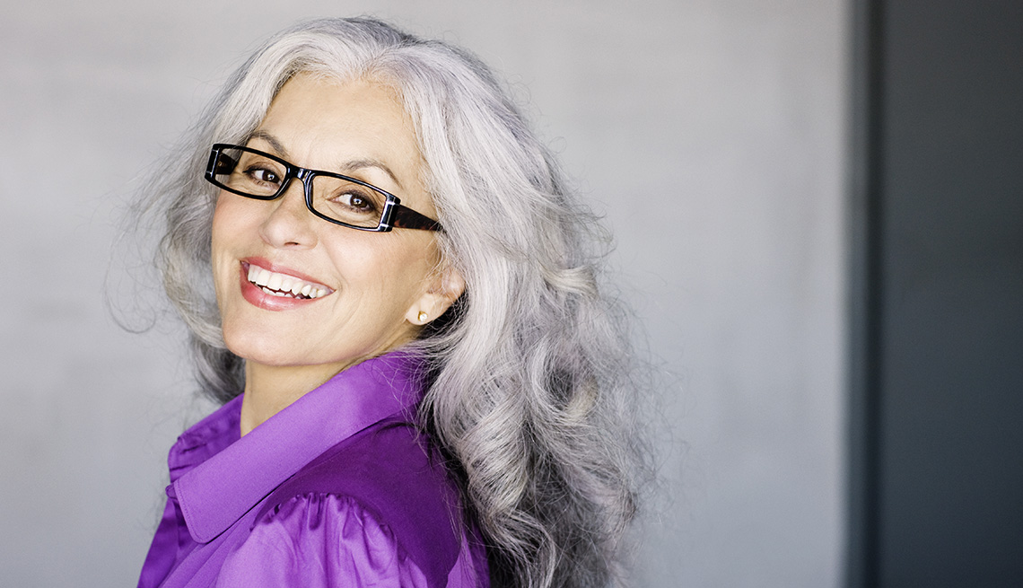 A woman wearing dark glasses and a purple shirt smiling for a photo
