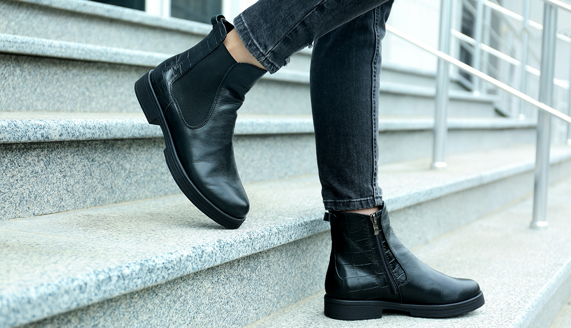 A closeup of a woman wearing stylish black boots standing on stairs