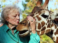 Betty White author of Betty and Friends - My Life at the Zoo kisses a giraffe 