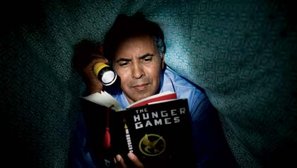 Mature man reading The Hunger Games in bed