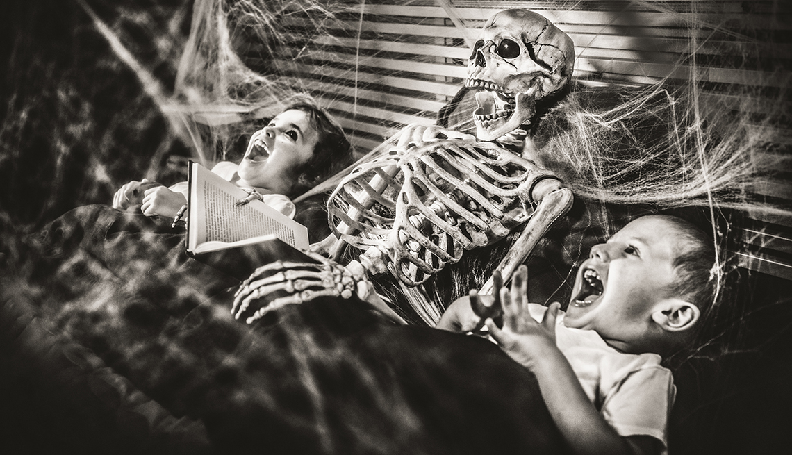 Little girl reading terror stories to her brother and a skeleton.