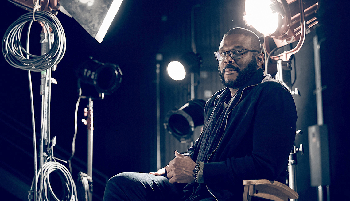 tyler perry sits in a directors chair in a studio