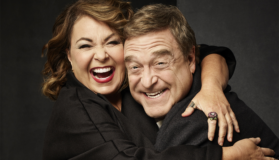 Roseanne Barr and John Goodman hugging and laughing