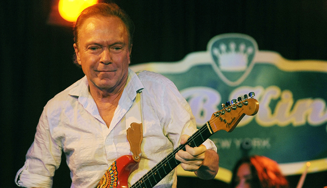 David Cassidy holding a guitar on stage.