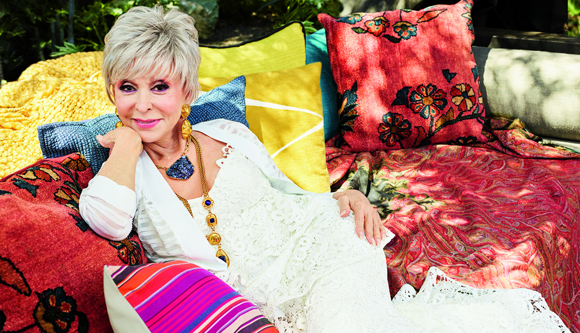 item 12 of Gallery image - Rita Moreno sitting on a couch outside.